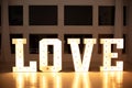 Illuminated Love sign in large letters near window. Love big white letters with led retro bulbs glowing.