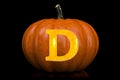 Glowing Letter D carved in pumpkin. Halloween font on black background, 3D rendering