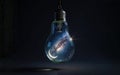 A glowing light bulb on a black background containing a night sky with stars and a moon inside, representing astronomy, science Royalty Free Stock Photo