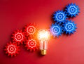 Glowing light bulb connected between blue and red gear wheels on red background. Royalty Free Stock Photo