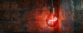 Glowing Light Bulb With a Cross Inside Hanging From Brick Wall Royalty Free Stock Photo