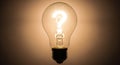 A glowing light bulb displays a white question mark inside, set against a dark Royalty Free Stock Photo