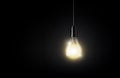 Glowing light bulb is hanging on dark black background for copy space, isolated, transparent vector illustration Royalty Free Stock Photo