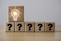 Glowing light bulb icon stands above blocks with question marks on wooden block for problem solving creative thinking innovation Royalty Free Stock Photo