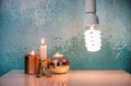 Glowing light bulb near burning candles on color table Royalty Free Stock Photo