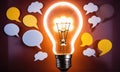 A glowing light bulb with speech bubbles around it, representing the birth of a new idea Royalty Free Stock Photo