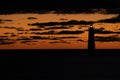 light house is glowing bright in fire skies of sunset on the bay