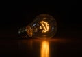 A glowing lightbulb on a dark surface, emitting a warm and inviting light. Royalty Free Stock Photo