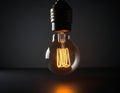 A glowing lightbulb on a dark surface, emitting a warm and inviting light. Royalty Free Stock Photo