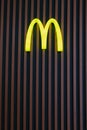 Glowing McDonald`s logo on the wooden facade of a fast food restaurant