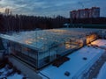 Glowing modern glass greenhouse in winter night, aerial view