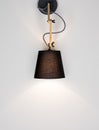 A glowing modern lamp on a light wall with free space. Black lamp