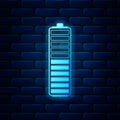 Glowing neon Battery charge level indicator icon isolated on brick wall background. Battery charging - power sign