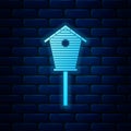 Glowing neon Bird house icon isolated on brick wall background. Nesting box birdhouse, homemade building for birds