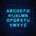 Glowing neon blue color alphabet font on dark brick wall background. Vector neon style letters. Royalty Free Stock Photo