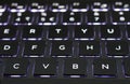 Glowing neon blue laptop keyboard. Close-up.