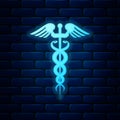 Glowing neon Caduceus medical symbol icon isolated on brick wall background. Medicine and health care concept. Emblem