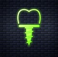 Glowing neon Dental implant icon isolated on brick wall background. Vector