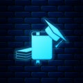 Glowing neon Graduation cap and book icon isolated on brick wall background. Vector Royalty Free Stock Photo