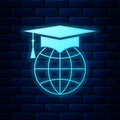 Glowing neon Graduation cap on globe icon isolated on brick wall background. World education symbol. Online learning or