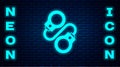 Glowing neon Handcuffs icon isolated on brick wall background. Vector