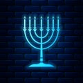 Glowing neon Hanukkah menorah icon isolated on brick wall background. Religion icon. Hanukkah traditional symbol