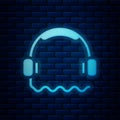 Glowing neon Headphones icon isolated on brick wall background. Support customer service, hotline, call center, faq Royalty Free Stock Photo