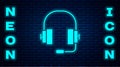 Glowing neon Headphones icon isolated on brick wall background. Support customer service, hotline, call center, faq Royalty Free Stock Photo