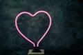 Glowing neon heart shape with black textured back