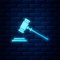 Glowing neon Judge gavel icon isolated on brick wall background. Gavel for adjudication of sentences and bills, court