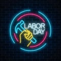 Glowing neon labor day sign in circle frames on dark brick wall background. World labor day symbol with hammer in hand