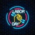 Glowing neon labor day sign in circle frames on dark brick wall background. World labor day symbol with wrench in hand.