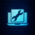 Glowing neon Laptop with wrench icon isolated on brick wall background. Adjusting, service, setting, maintenance, repair Royalty Free Stock Photo