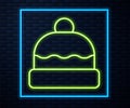 Glowing neon line Beanie hat icon isolated on brick wall background. Vector
