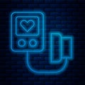 Glowing neon line Blood pressure icon isolated on brick wall background. Vector