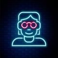 Glowing neon line Hacker or coder icon isolated on brick wall background. Programmer developer working on code, coding