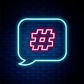 Glowing neon line Hashtag speech bubble icon isolated on brick wall background. Concept of number sign, social media