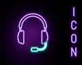 Glowing neon line Headphones with microphone icon isolated on black background. Concept object for listening to music Royalty Free Stock Photo