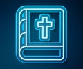 Glowing neon line Holy bible book icon isolated on blue background. Vector