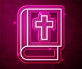 Glowing neon line Holy bible book icon isolated on red background. Vector