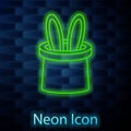 Glowing neon line Magician hat and rabbit ears icon isolated on brick wall background. Magic trick. Mystery