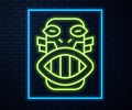 Glowing neon line Mexican mayan or aztec mask icon isolated on brick wall background. Vector