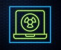 Glowing neon line Nuclear laptop icon isolated on brick wall background. Vector