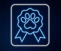 Glowing neon line Pet award symbol icon isolated on brick wall background. Badge with dog or cat paw print and ribbons Royalty Free Stock Photo