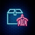 Glowing neon line Plane and cardboard box icon isolated on brick wall background. Delivery, transportation. Cargo Royalty Free Stock Photo