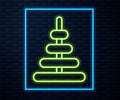 Glowing neon line Pyramid toy icon isolated on brick wall background. Vector