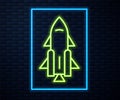 Glowing neon line Rocket ship with fire icon isolated on brick wall background. Space travel. Vector Royalty Free Stock Photo