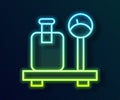 Glowing neon line Scale with suitcase icon isolated on black background. Logistic and delivery. Weight of delivery