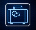 Glowing neon line Suitcase for travel icon isolated on brick wall background. Traveling baggage sign. Travel luggage Royalty Free Stock Photo