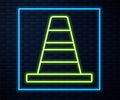 Glowing neon line Traffic cone icon isolated on brick wall background. Vector